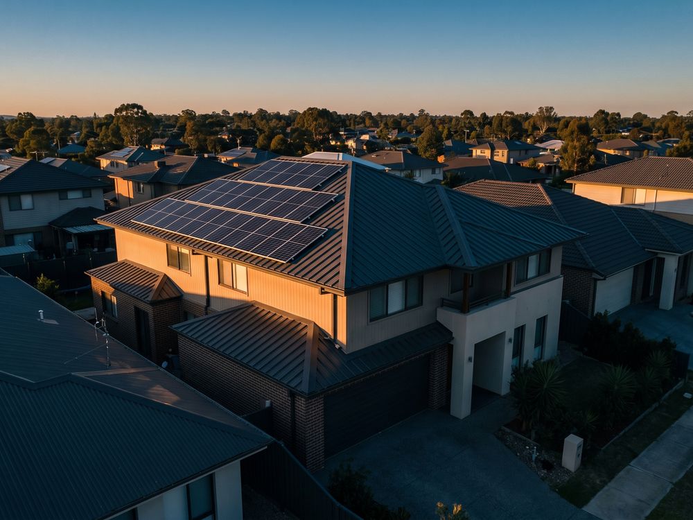 An aerial view of a modern two-story home in Plano with a dark roof and solar panels.